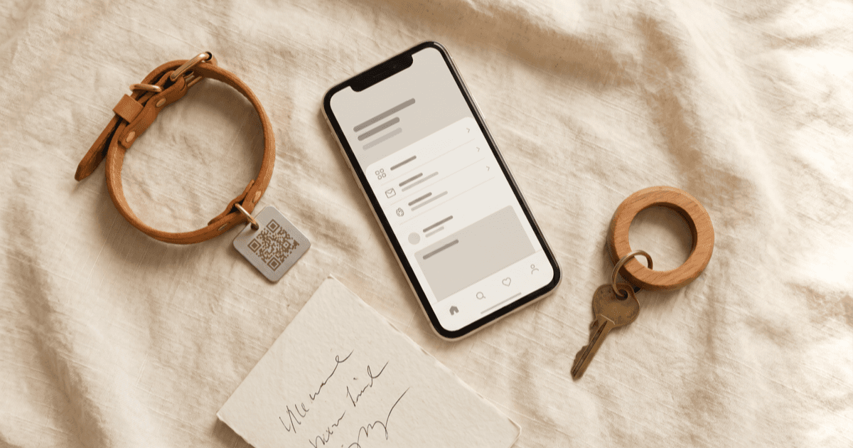 A flat-lay on warm cream linen of a smartphone with a privacy screen, a leather pet collar, a folded note pad, and a small house key on a wooden key ring.