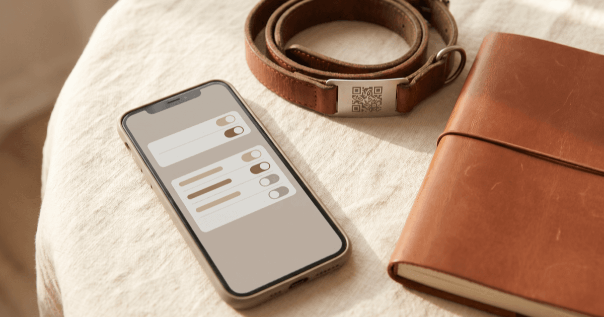 A flat-lay on warm cream linen of a smartphone showing a calm privacy settings screen beside a pet collar with a small QR-style tag and a closed notebook in soft natural light.